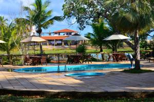 a swimming pool with tables and umbrellas and a resort at Pousada Mar de Estrelas in São Miguel do Gostoso
