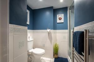 La salle de bains est pourvue de toilettes et d'un mur bleu. dans l'établissement Rustic cabin located in a serene forest setting, à Southampton