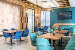 a restaurant with wooden tables and blue chairs at Hotel Omni in Valjevo