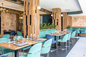 a dining room with wooden tables and blue chairs at Hotel Omni in Valjevo