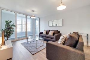 a living room with two couches and a glass table at Roomspace Serviced Apartments - Brewers Lane in Richmond