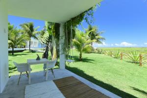 a patio with a table and chairs and a lawn at Pe na Areia Boutique Hotel in Japaratinga