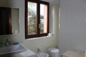 een badkamer met een toilet, een wastafel en een raam bij Villa Grace in La Maddalena
