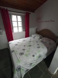 1 dormitorio con cama con edredón y ventana en Chácara em Ibiúna São Roque a 70km de SP com piscina e wi-fi, en Ibiúna