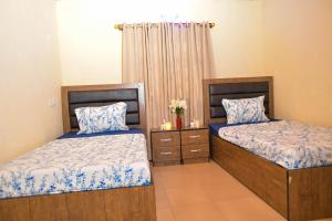 1 dormitorio con 2 camas con sábanas azules y blancas en Living Green APARTMENTS AIRPORT PICK UP en Benin City