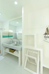 a white bathroom with a sink and a mirror at Pe na Areia Boutique Hotel in Japaratinga