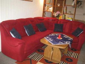 un sofá rojo en una sala de estar con mesa en Ferienwohnung Klingelhöfer E-III-2-6, en Altenau