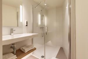 een witte badkamer met een douche en een wastafel bij B&B HOTEL Lille Lillenium Eurasanté in Lille