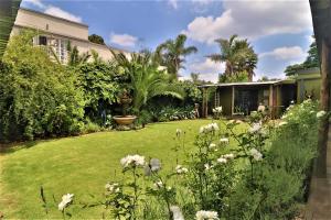 podwórko z domem i trawnikiem z kwiatami w obiekcie The Ranch Guesthouse w mieście Potchefstroom