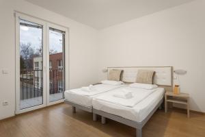 a white bedroom with a bed and a large window at Prague City Residence in Prague