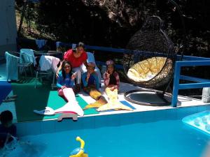 een groep kinderen die voor een zwembad zitten bij Anilao Cliffhouse in Mabini