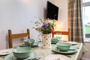 een tafel met borden en glazen en een vaas met bloemen bij Queen Bower Farm Lodge in Alverstone