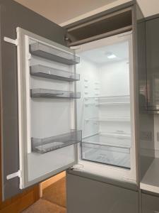 an empty refrigerator with its door open in a kitchen at No 10 @Short Stays in Basingstoke