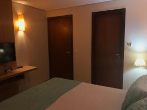 sypialnia z łóżkiem z telewizorem i drzwiami w obiekcie Kariri Beach - Suíte Standard w mieście Cumbuco