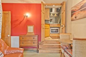 uma cozinha com paredes vermelhas e um armário de madeira em Bridge Cottages - Bridge Suite em Coniston