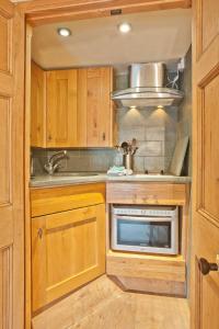 uma cozinha com armários de madeira, um lavatório e um micro-ondas em Bridge Cottages - Bridge Suite em Coniston