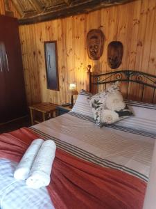Schlafzimmer mit einem großen Bett und Holzwänden in der Unterkunft Honne-Pondokkies in Hondeklipbaai