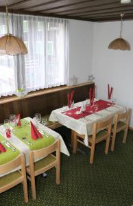 un comedor con 2 mesas y sillas con servilletas rojas en Hotel Péz Ault, en Disentis