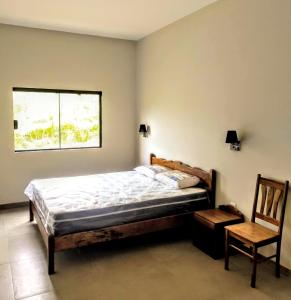 ein Schlafzimmer mit einem Bett, einem Stuhl und einem Fenster in der Unterkunft Casa das Lavandas represa de Nazaré Paulista in Nazaré Paulista