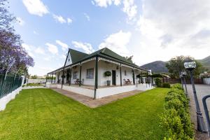 Biały dom z zielonym dachem i dziedzińcem w obiekcie Victorian Square Guesthouse w mieście Graaff-Reinet