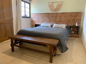 1 dormitorio con cama con cabecero de madera y banco en Casa en el centro de Salta - Casaguemessalta en Salta