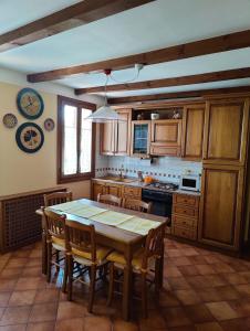 y cocina con mesa de madera, sillas y fogones. en Casa Vacanze Monte Villa en Pieve di Soligo