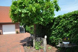 un albero di fronte a una casa con una recinzione di Ferienwohnung Martens 65344 a Moormerland
