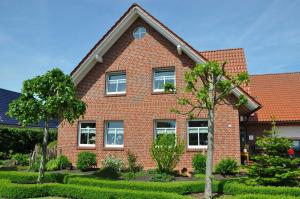 una casa di mattoni rossi con un albero di fronte di Ferienwohnung Martens 65344 a Moormerland