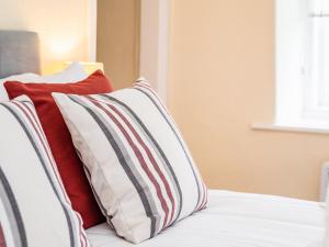 a bed with red and white pillows on it at The Nest in Helmsley