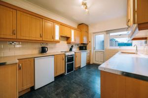 uma cozinha com armários de madeira e electrodomésticos brancos em Norton Village View By Horizon Stays em Stockton-on-Tees