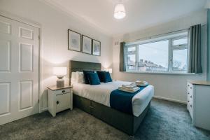 a bedroom with a bed with blue pillows and a window at Norton Village View By Horizon Stays in Stockton-on-Tees