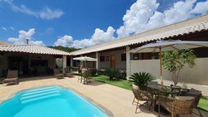 uma piscina com cadeiras e mesas e um guarda-sol em Pousada Vila Santa Maria em Pirenópolis