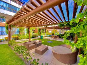 un patio con una pérgola de madera con sillas y mesas en Condomínio Mediterranee Residence por Be My Guest, en Aquiraz