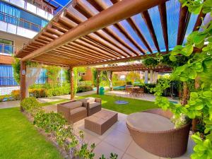 a patio with a wooden pergola with chairs and tables at Condomínio Mediterranee Residence por Be My Guest in Aquiraz