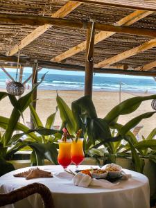 a table with two glasses of orange juice on the beach at Casa na Praia Tofo- beach front hotel in Praia do Tofo
