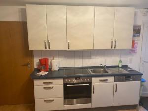 una cocina con armarios blancos y fregadero en Haus Zeichner 2 Zimmer Ferienwohnung en Feldberg
