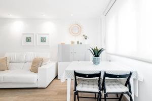 sala de estar blanca con mesa y sofá en Casa Brasil - 1ª Linea Playa con Parking Incluido, en Cádiz