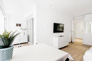 Una sala de estar blanca con una mesa y un televisor. en Casa Brasil - 1ª Linea Playa con Parking Incluido, en Cádiz