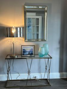 uma mesa com um candeeiro e um espelho na parede em Macemia Place LLC em Baltimore