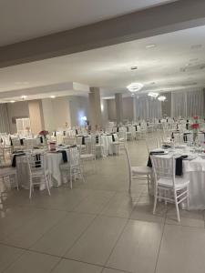 um salão de banquetes com mesas brancas e cadeiras brancas em Hotel Villa Ruggiero em Brusciano