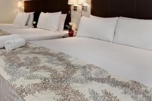 two beds in a hotel room with white sheets at Best Western Chiswick Palace & Suites London in London