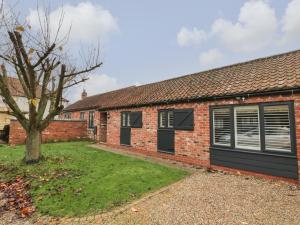 a brick house with a garage and a tree at Well Cottage in Beverley