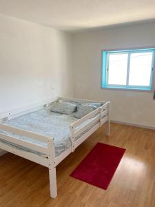 uma cama branca num quarto com um tapete vermelho em 3 bedrooms villa with city view private pool and enclosed garden at Sao Miguel do Prado 