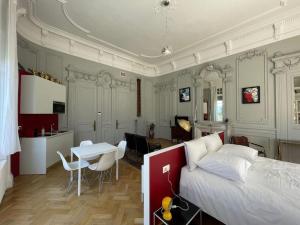 a bedroom with a bed and a table and a kitchen at Suite Célestine Palace Excelsior vue lac in Aix-les-Bains