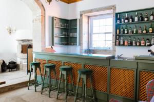 um bar com bancos verdes e garrafas de álcool em Quinta do Convento de Val´ Pereiras em Ponte de Lima