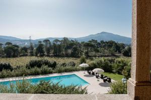 una piscina con sombrillas y vistas a las montañas en Quinta do Convento de Val´ Pereiras, en Ponte de Lima