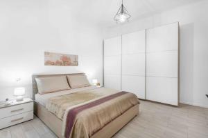 ein weißes Schlafzimmer mit einem großen Bett und einem Nachttisch in der Unterkunft ELLE Boutique [Milano-Lissone-Monza] in Lissone
