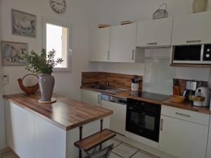 a kitchen with white cabinets and a wooden counter top at Les Aludes in La Destrousse