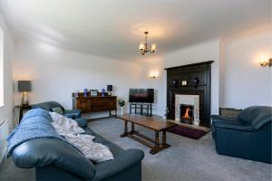 a living room with a couch and a table and a fireplace at H C property - Burnlea Cottage in Copley