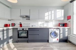 a white kitchen with a washing machine in it at Roomspace Serviced Apartments - Brewers Lane in Richmond
